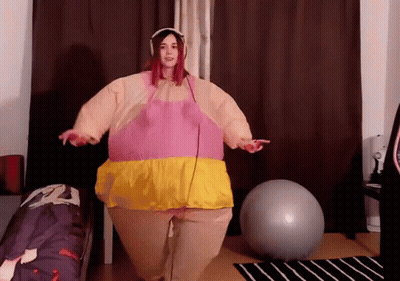 Woman In Pink And Yellow Inflatable Costume With Exercise Ball GIF