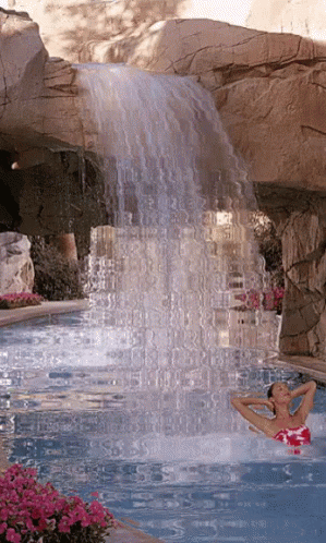 Woman In Pink Bathing Suit Swimming Under Waterfall GIF