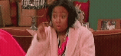 Woman In Pink Coat Surprised On Couch GIF
