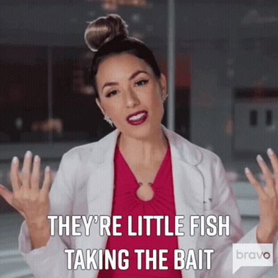 Woman In Pink Dress And White Coat Says They're Little Fish Taking The Bait GIF