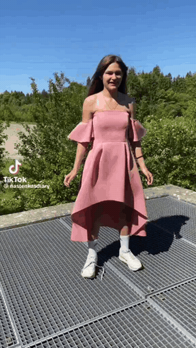 Woman In Pink Dress And White Sneakers On Metal Fence GIF