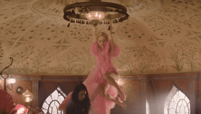 Woman In Pink Dress Flying Before Chandelier GIF