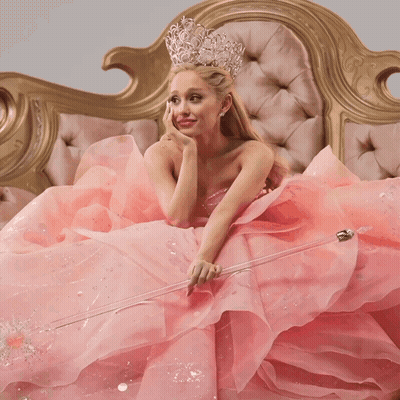 Woman In Pink Dress Holding Wand On Couch GIF