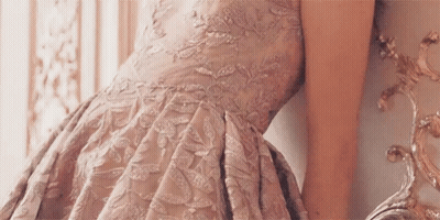 Woman In Pink Dress Leaning Against Wall Looking In Mirror GIF