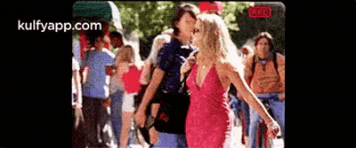 Woman In Pink Dress Next To Man In Blue Shirt In Front Of Crowd GIF