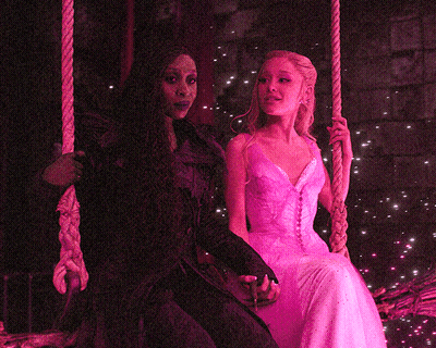 Woman In Pink Dress Sitting Next To Woman In Black Dress On Swing GIF