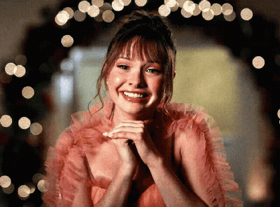 Woman in Pink Dress Smiling in Front of Christmas Tree