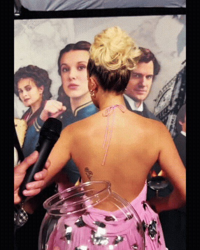 Woman In Pink Dress Standing In Front Of Poster GIF