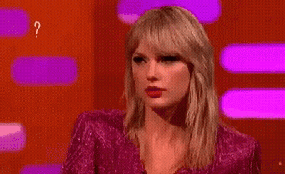 Woman In Pink Dress Surrounded By Question Marks Making Funny Face GIF