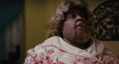 Woman In Pink Floral Dress And Pearls On Bed GIF