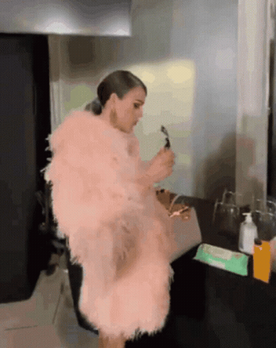 Woman In Pink Fur Coat Before Mirror GIF