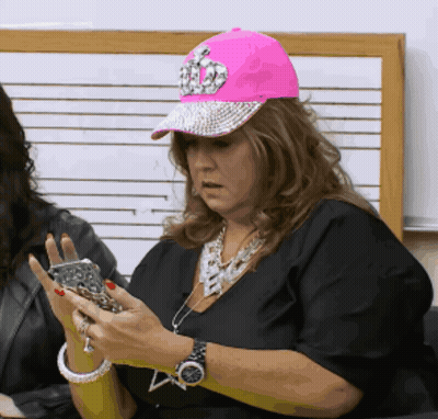 Woman In Pink Hat And Black Shirt Looking At Phone GIF