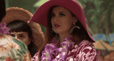 Woman In Pink Hat And Lei Standing In Crowd GIF