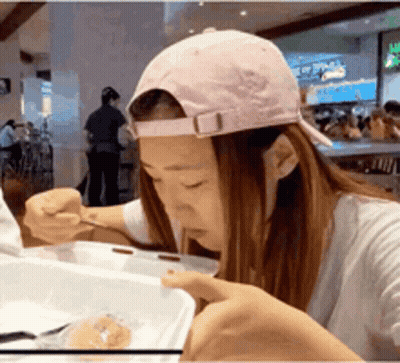 Woman In Pink Hat Eating From Container GIF