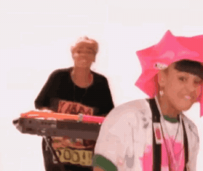 Woman In Pink Hat Holding Umbrella Next To Woman With Keyboard GIF
