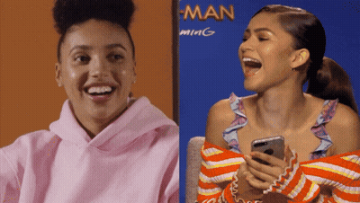 Woman In Pink Hoodie Laughing Next To Woman In Orange Sweater GIF