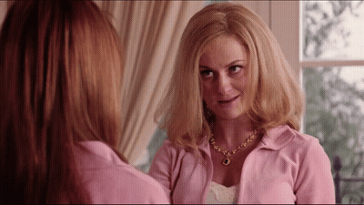 Woman In Pink Jacket And Necklace Admiring Reflection GIF