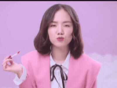 Woman In Pink Jacket Holding Lip Gloss GIF
