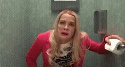 Woman In Pink Jacket Holding Toilet Paper In Public Restroom GIF