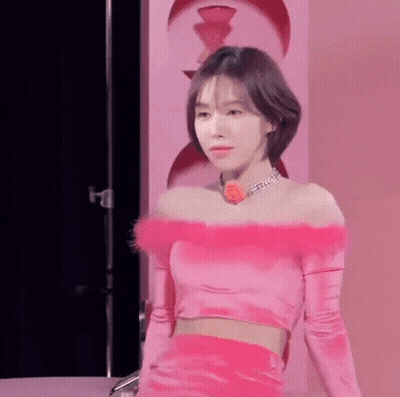 Woman In Pink Off-Shoulder Crop Top And Skirt By Pink Wall GIF