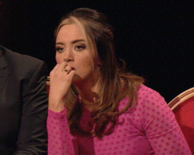 Woman In Pink Polka Dot Shirt Sitting With Hand To Mouth GIF