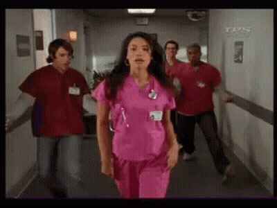 Woman In Pink Scrubs Walking Down Hallway GIF