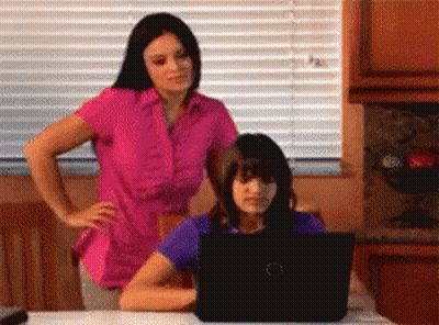 Woman In Pink Shirt And Girl In Purple Shirt Looking At Laptop GIF