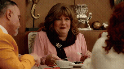 Woman In Pink Shirt And Scarf Eating At Table GIF