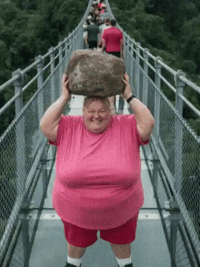 Woman In Pink Shirt Carrying Rock On Bridge GIF