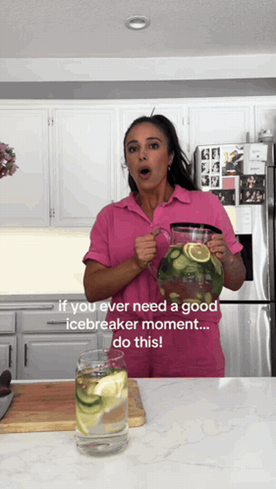 Woman In Pink Shirt Holding Lemon Cucumber Water Pitcher GIF