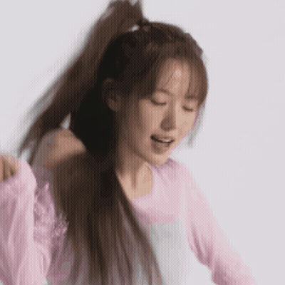 Woman In Pink Shirt Holding Ponytail Smiling GIF
