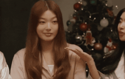 Woman In Pink Shirt In Front Of Christmas Tree GIF