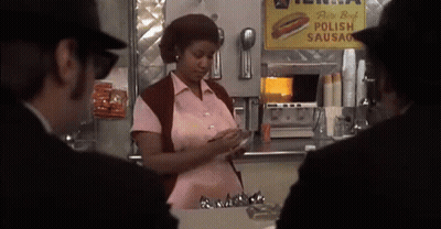 Woman In Pink Shirt In Front Of Polish Sausage Sign GIF