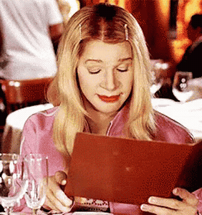 Woman In Pink Shirt Looking At Menu In Restaurant GIF