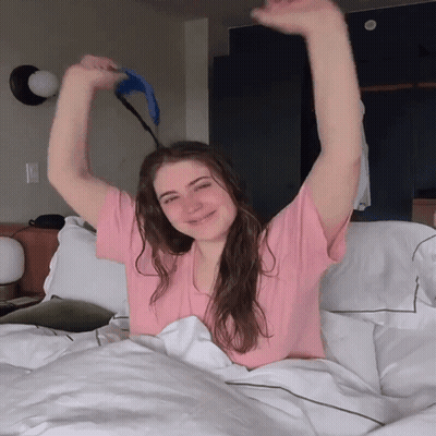 Woman In Pink Shirt Lying On Bed GIF