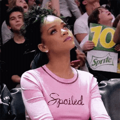 Woman In Pink Shirt Saying Spoiled Holding Sprite Sign In Crowd GIF