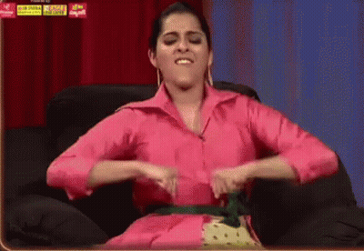 Woman In Pink Shirt Sitting With Hands On Stomach GIF