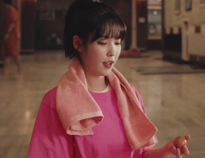 Woman In Pink Shirt Smiling Holding Hair In Bun GIF