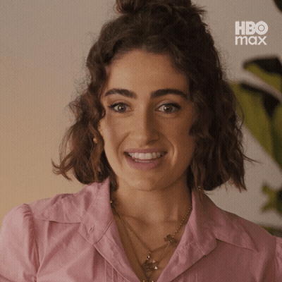 mujer de camisa rosa sonriendo frente al letrero de hbo max GIF
