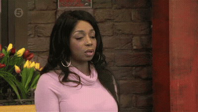 Woman In Pink Sweater In Front Of Brick Wall With Number 5 GIF