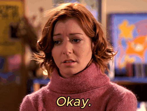 Woman In Pink Sweater Says Okay In Yellow Letters GIF