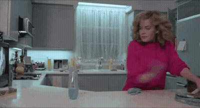 Woman In Pink Sweater Standing In Kitchen GIF