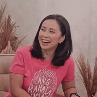 Woman In Pink T-Shirt With Fingerprint Smiling On Couch GIF