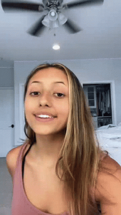 Woman In Pink Tank Top Smiling In Front Of Ceiling Fan GIF