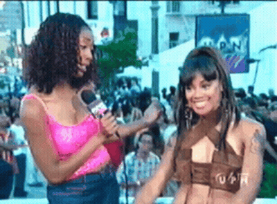 Woman In Pink Tank Top Talking Into Microphone Next To Another Woman GIF