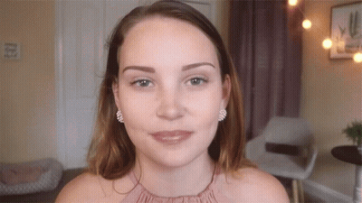 Woman In Pink Top With Earrings Looking At Camera GIF