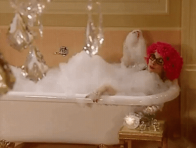 Woman In Pink Wig Lying In Bubble Bath GIF