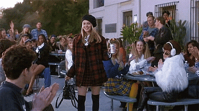 Woman In Plaid Dress And Beret Before Applauding Crowd GIF