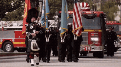 Woman In Plaid Jacket And Man Playing Bagpipes GIF