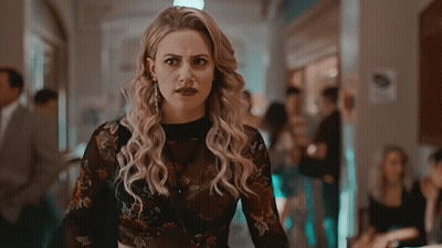 Woman In Plaid Shirt And Choker Standing Next To Another Woman GIF